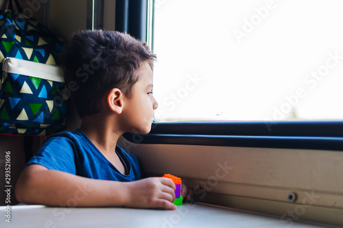 6 years old boy travelling in the train. looks out the window