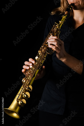 soprano saxophone in hands on a black background