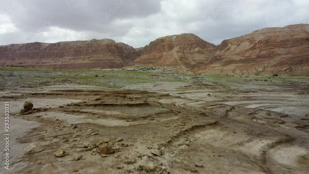 Dead sea desert green after the rain, fly over, red mountain background, cloudy sky, drone shot Dead sea desert green after the rain, fly over, red mountain background, cloudy sky, drone shot