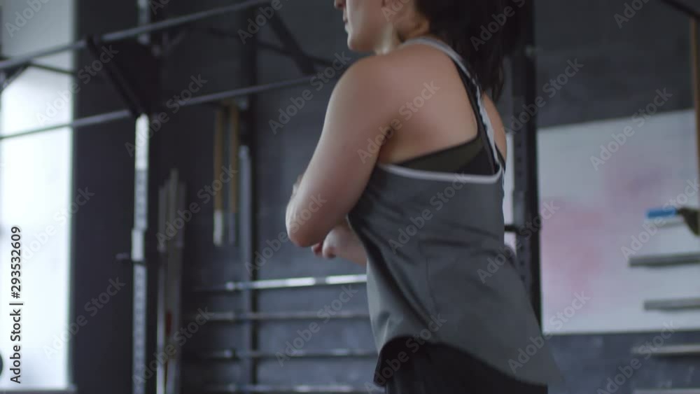 Tilt down slow motion shot of young sportswoman doing side swings with jumping rope while having cardio workout in gym Tilt down slow motion shot of young sportswoman doing side swings with jumping rope while having cardio workout in gym