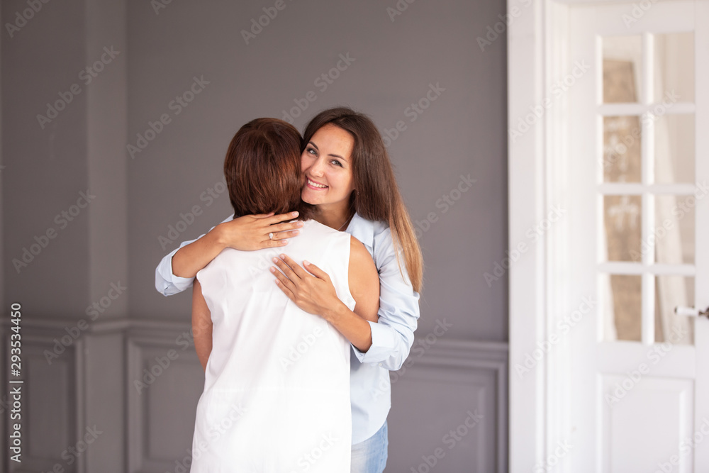 Adult woman hugs her elderly mother and they both smiling Adult woman hugs her elderly mother and they both smiling