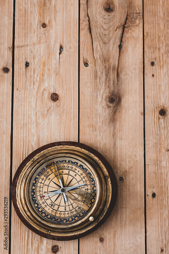OLD COMPASS ON RUSTIC WOOD BACKGROUND. TRAVEL THE WORLD