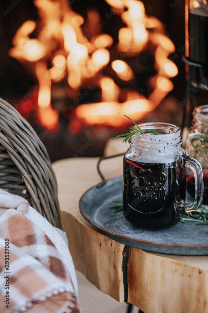 Decorated Christmas table with a glass of mulled wine on the background of a burning fireplace