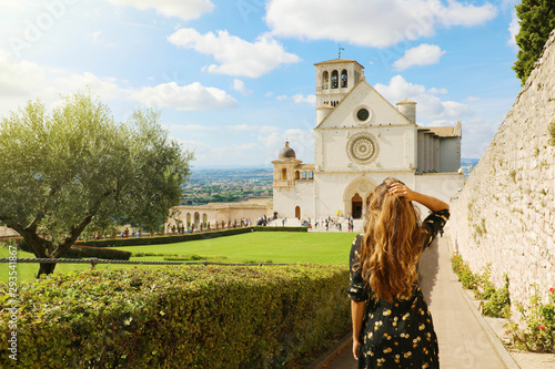 Tourism in Italy. Back view of beautiful girl enjoying view of the Basilica of Saint Francis of Assisi in Umbria, Italy. photo