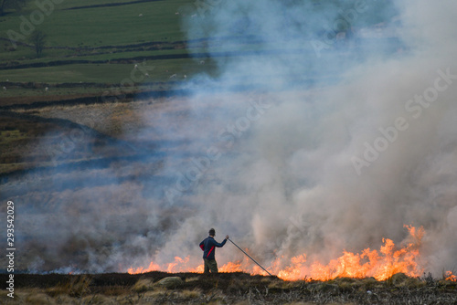 Farmer beating fire to control burning of heather [3]