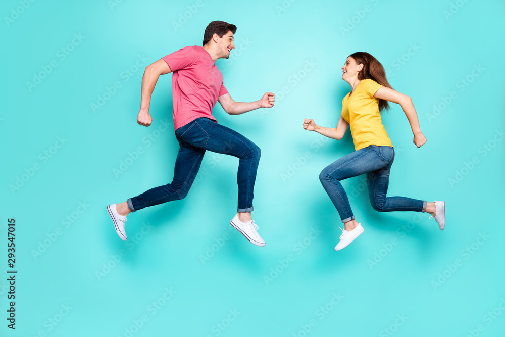 Full length body size profile side view of nice attractive sportive active cheerful cheery couple running jumping in air having fun isolated over bright vivid shine vibrant green turquoise background