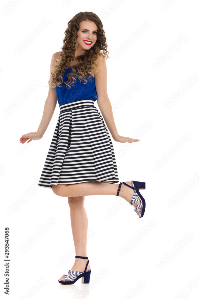 Happy Young Woman In Striped Skirt And High Heels Is Standing On One Leg Happy Young Woman In Striped Skirt And High Heels Is Standing On One Leg