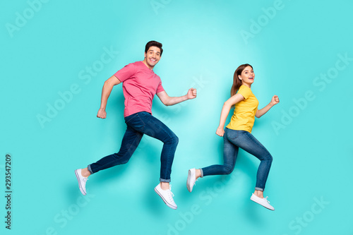 Full length body size profile side view of nice attractive funny cheerful cheery couple running fast speed in air having fun isolated over bright vivid shine vibrant green turquoise background