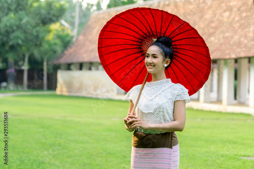 Beautiful Thai girl in traditional dress costume and red umbrella at Thai temple photo