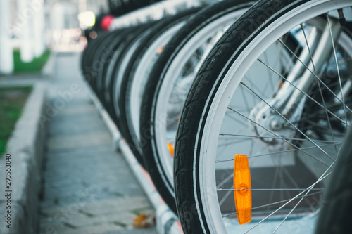 Close up shot of many rent bicycles wheels standing in a row with blurred background