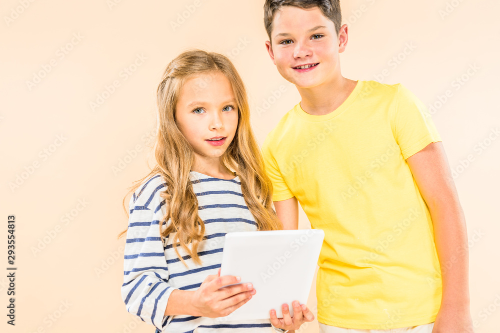 two smiling kids using digital tablet isolated on pink two smiling kids using digital tablet isolated on pink