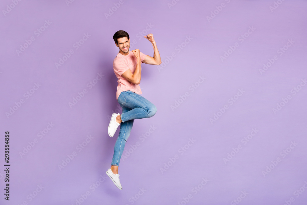 Full length photo of amazing guy jumping high at sports competitions supporting favorite team wear casual outfit isolated on purple color background Full length photo of amazing guy jumping high at sports competitions supporting favorite team wear casual outfit isolated on purple color background
