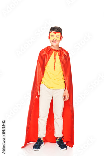 full length view of smiling kid in mask and hero cloak on white