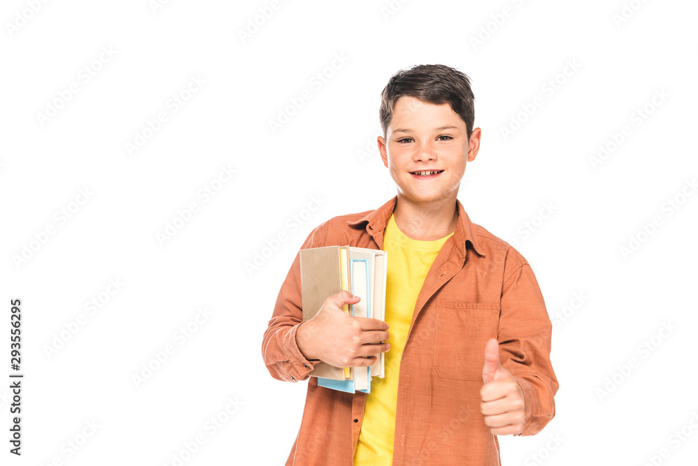 front view of smiling kid holding books and showing thumb up isolated on white front view of smiling kid holding books and showing thumb up isolated on white