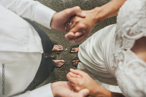 Fototapeta Naklejka Na Ścianę i Meble -  Happy couple on the beach. Close-up of bride and groom holding hand walking on beautiful beach in summer.