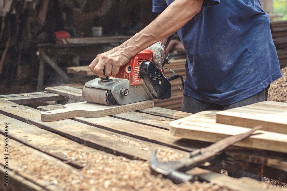 Carpenter sanding wood with belt sander at workshop in wooden cutting board project or woodworking carpentry Carpenter sanding wood with belt sander at workshop in wooden cutting board project or woodworking carpentry