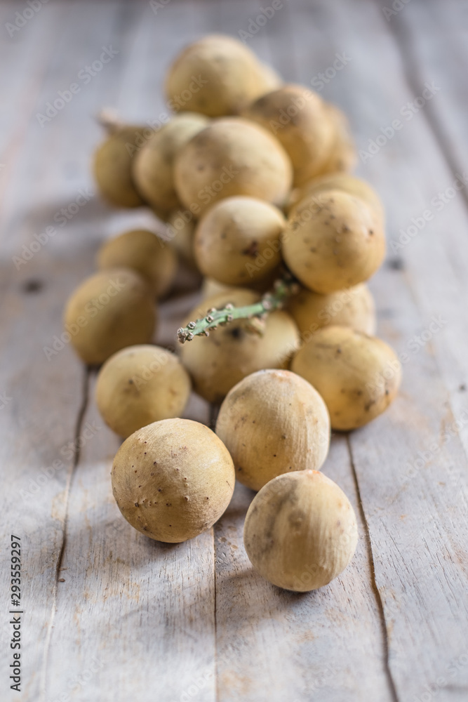 Fototapeta premium Clusters of exotic Thai fruit called Longkong or lansium parasiticumor southern langsat on wooden table and background. It is a famous sweet tropical fruit in southeast asia.