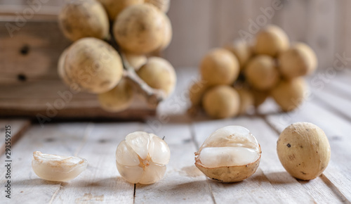 Mix of peeled and clusters whole of exotic Thai fruit called Longkong or lansium parasiticumor southern langsat on wooden table and background. It is a famous sweet tropical fruit in southeast asia.