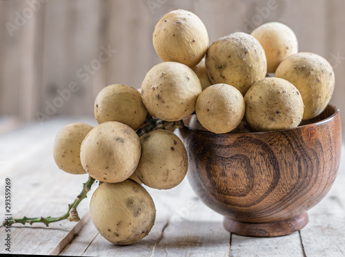 Clusters of exotic Thai fruit called Longkong or lansium parasiticumor southern langsat on wooden table and background. It is a famous sweet tropical fruit in southeast asia.