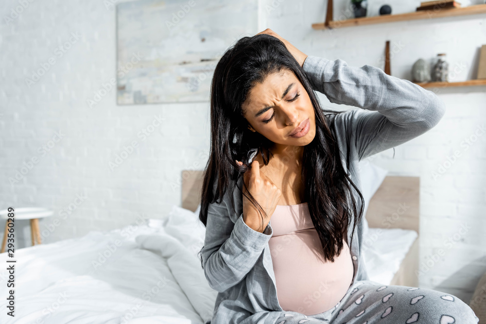 Φωτογραφία african american pregnant woman in pajamas feeling pain in apartment