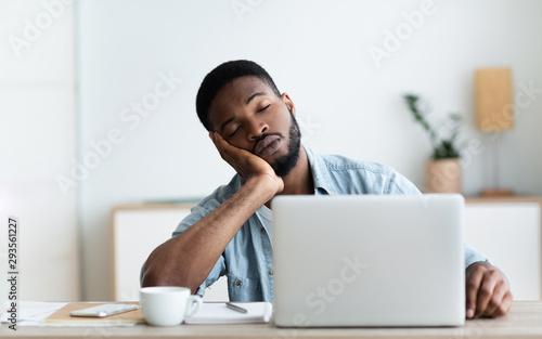 Exhausted African American worker felt asleep at workplace photo