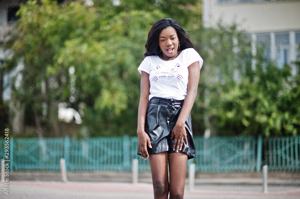 African american dark skinned slim model posed in a black leather shorts and white t-shirt.