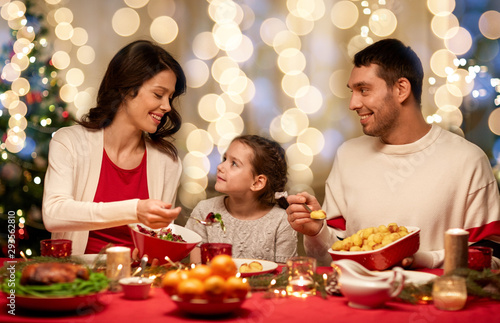 holidays  family and celebration concept - happy mother  father and little daughter having christmas dinner at home