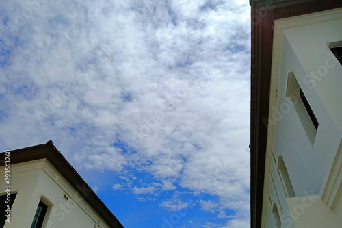 Low angel view of white cloud and blue sky between two houses.