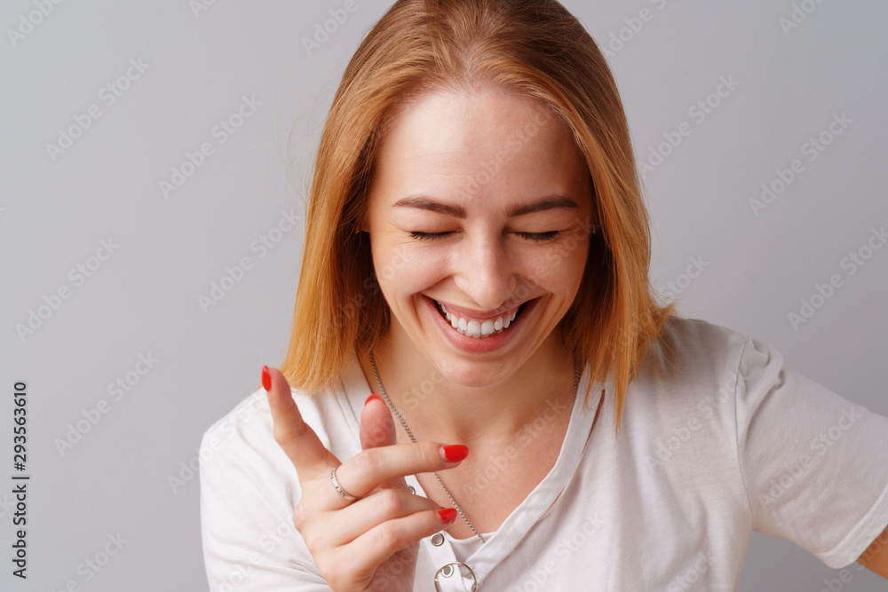 Portrait of joyful blonde young cute woman laughing over a gray background Portrait of joyful blonde young cute woman laughing over a gray background