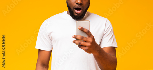Surprised african american guy checking social networks on smartphone