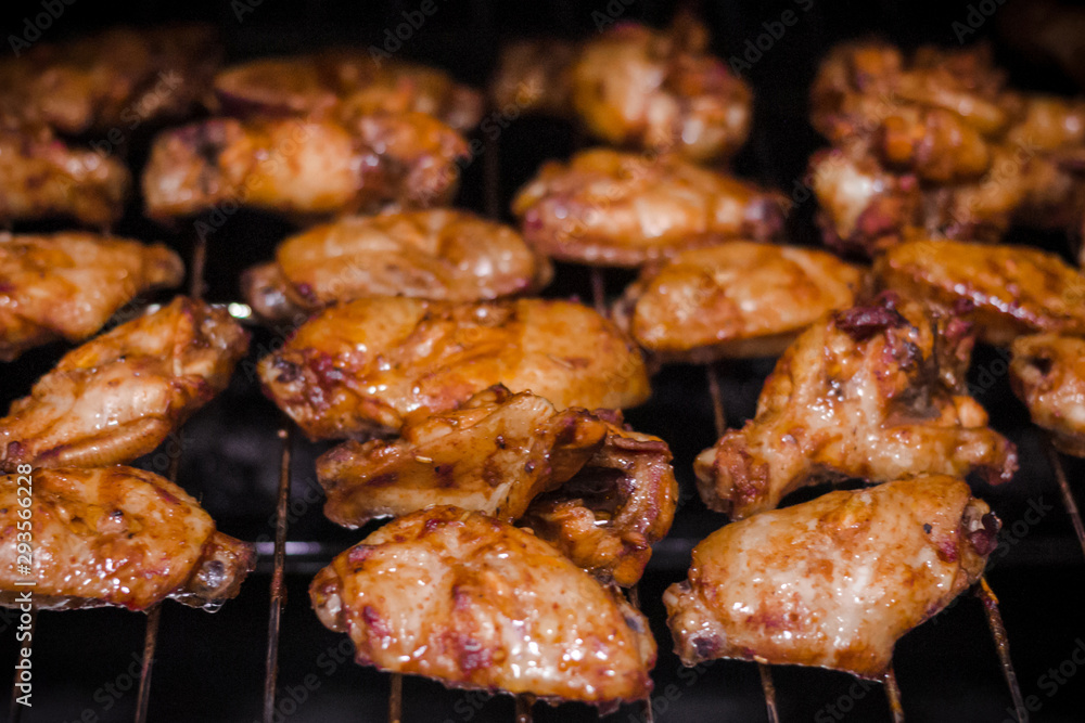 homemade spicy marinated chicken wings and wing stick on barbecue (BBQ) grill ready for the family party night. buffalo chicken wings ready to serve customers in the restaurant. selective focus photo.