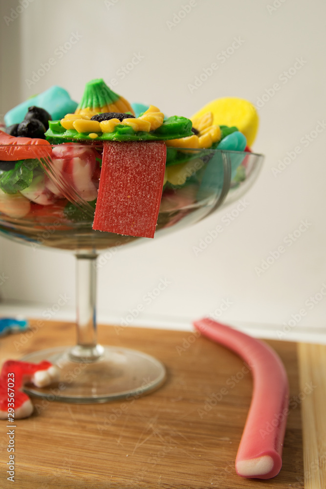 Multi-colored marmalade sweets of different sizes lie in a glass candy holder