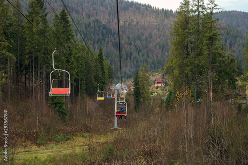 Old ski lifts with people ride through pine forest © dmf87