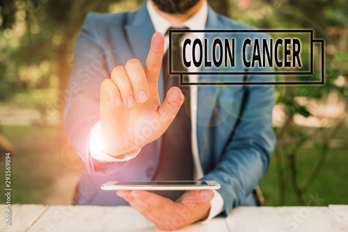Handwriting text writing Colon Cancer. Conceptual photo the development of cancer cells from the colon or rectum Businessman with pointing finger in front of him