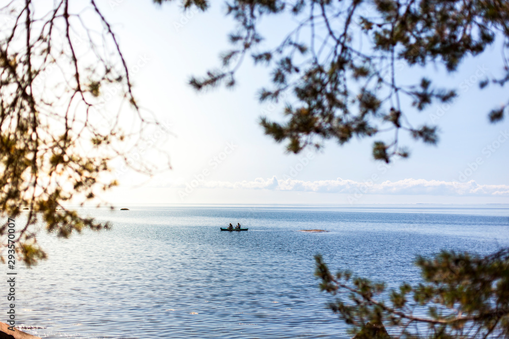 Ocean kayaking near coast. Kajak fahren auf offenem Meer  nahe der Küste. Blick durch Bäume auf Kajakfahrer.
