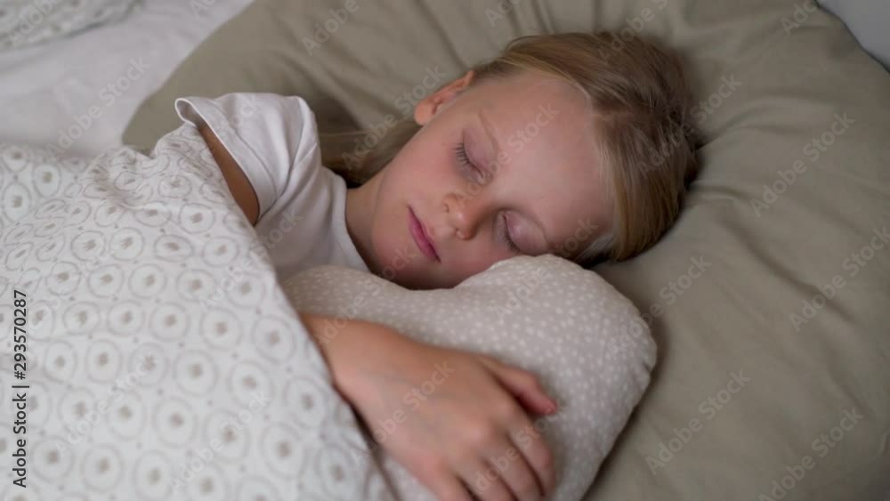 Close-up, kid blonde girl sleeping soundly sweetly in a crib in the bedroom hugging a cloud pillow, motion camera Close-up, kid blonde girl sleeping soundly sweetly in a crib in the bedroom hugging a cloud pillow, motion camera