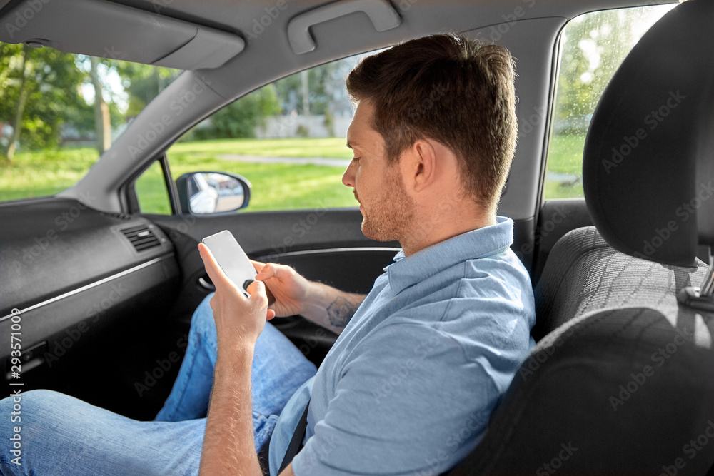 transport, taxi and communication concept - smiling male passenger using smartphone on back seat of taxi car