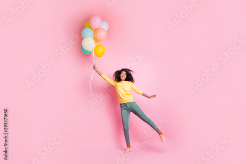 Full length photo of funky childish dreamy african girl hold many balons try fly in air enjoy holidays anniversary wear good look outfit sneakers isolated over pink color background photo