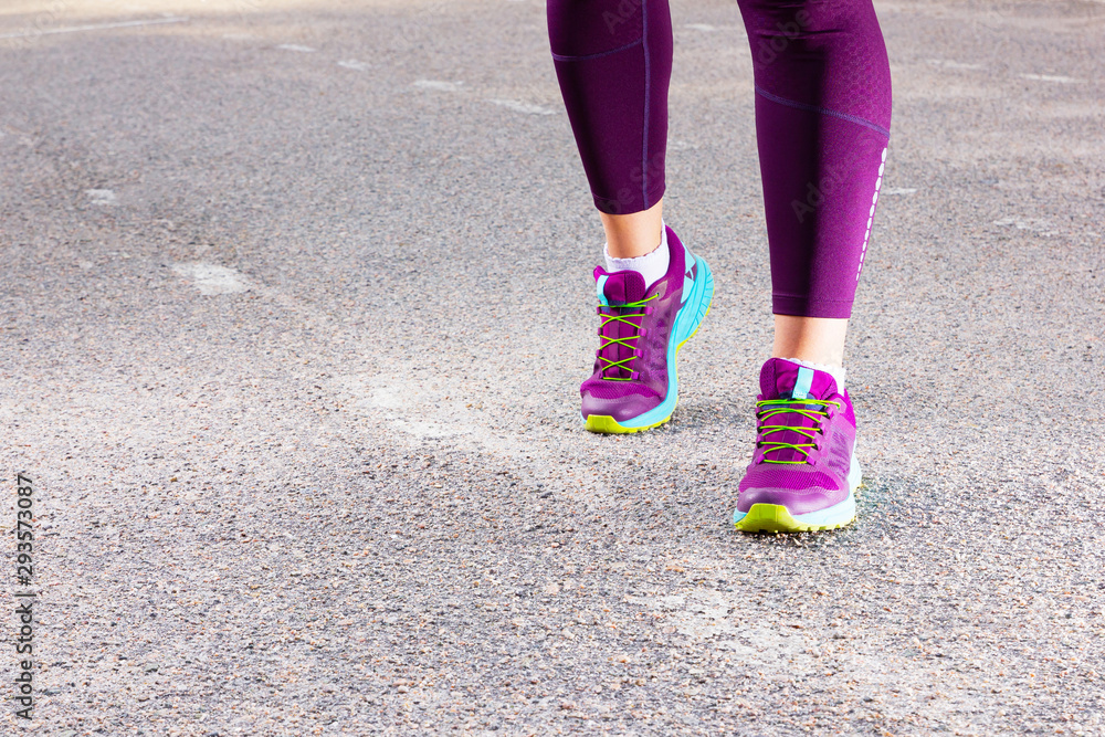 Sporty woman running in sneakers. Runner feet running on road close up on shoe. Young fitness woman running. Fitness and workout wellness concept