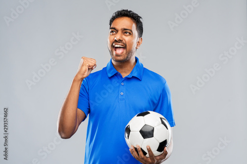 sport, leisure games and success concept - happy indian man or football fan with soccer ball celebrating victory over grey background