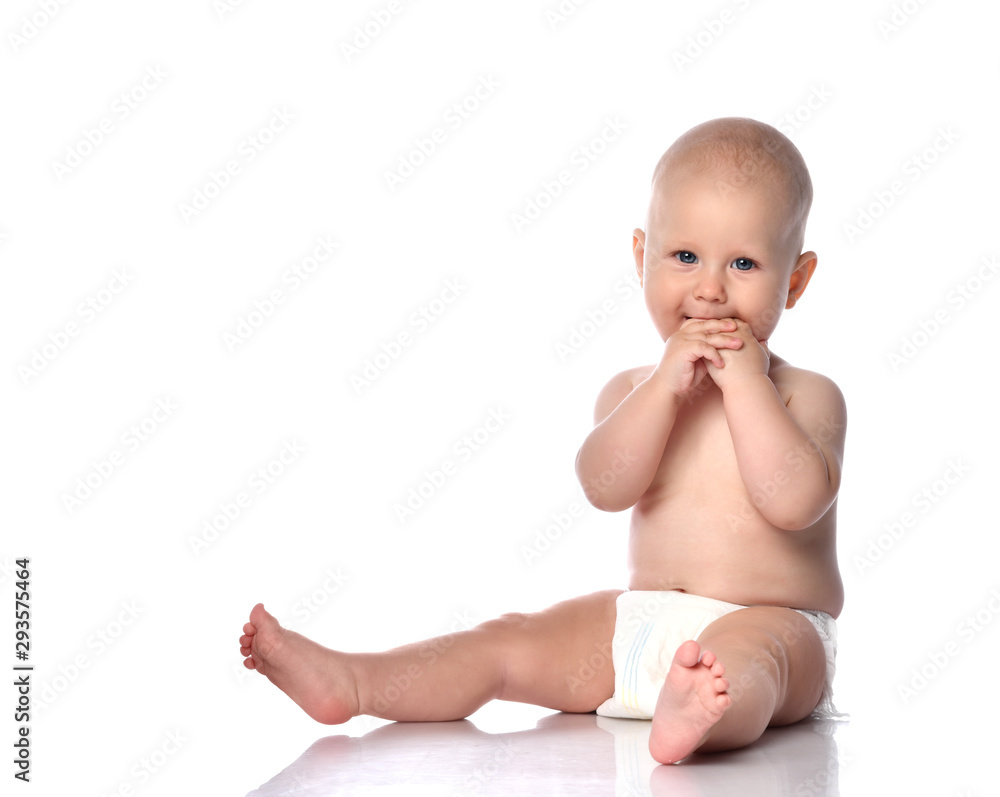 Infant child baby boy toddler sitting in diaper happy smiling eating hands playing isolated on white Infant child baby boy toddler sitting in diaper happy smiling eating hands playing isolated on white