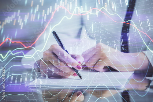 Double exposure of hands making notes with forex chart huds. Stock market concept.