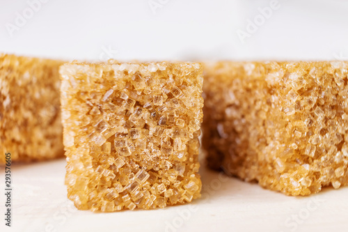 Cane sugar cubes on a white wooden background close-up. Minimalism, place for text. Macro