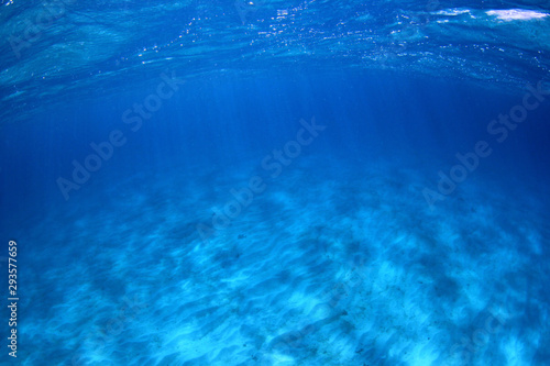 Underwater background of clear blue water on sandy sea floor