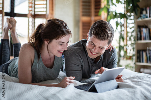 Young adult couple looking at a digital tablet together in bed photo