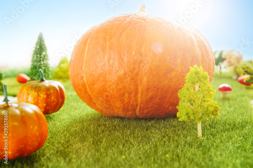 Orange plastic pumpkins on a green meadow with green grass. Macro shooting. Fairy tale.
