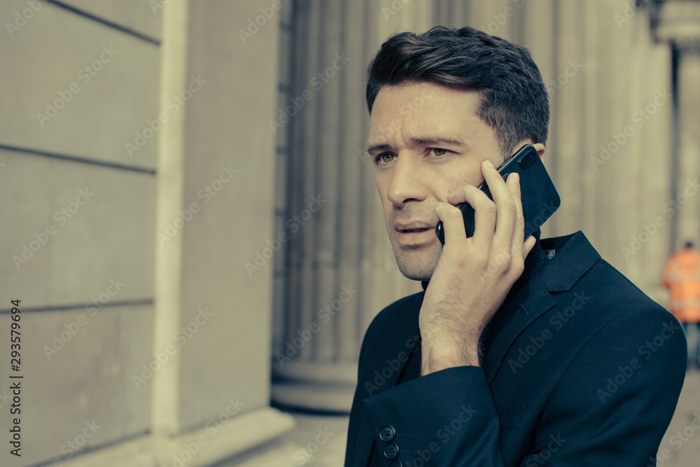 Young attractive man wearing black speaking on a phone outside with a serious face. Young attractive man wearing black speaking on a phone outside with a serious face.