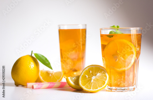 Glasses of ice tea with lemon slices and mint on white background