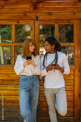 Young multiracial couple using their mobile phone on a wooden background.