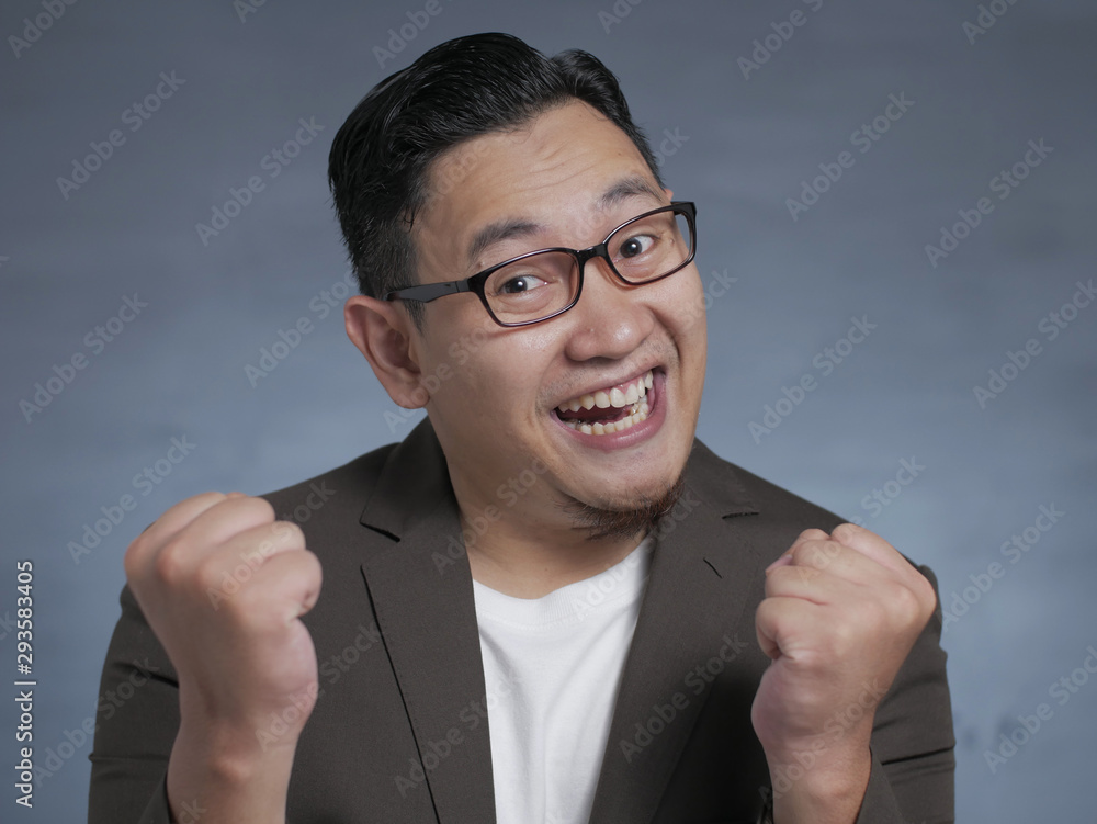 Happy Asian businessman smiling and shows winning gesture Happy Asian businessman smiling and shows winning gesture